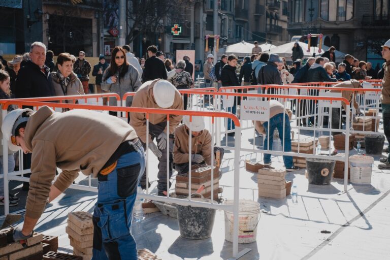 Les parelles de joves paletes, alçant les columnes a la cèntrica plaça Sant Domènec de Manresa. | Foto: Carla Baraldés/Gremi de Constructors de Manresa i Comarques.